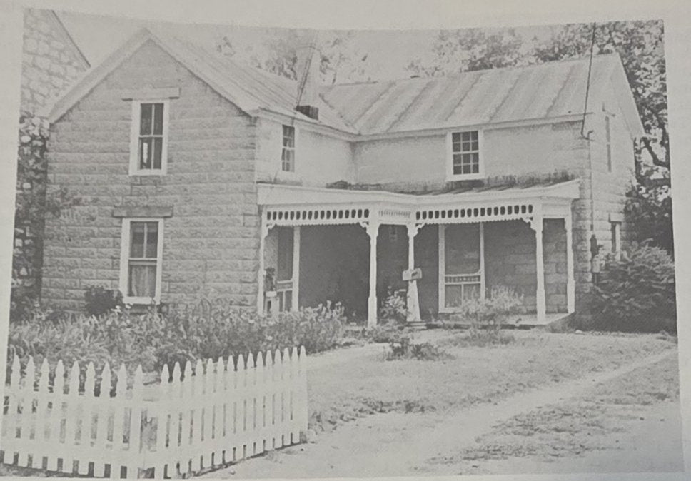 The rock house at 421 West Main Street with its gingerbread porch and white picket fence